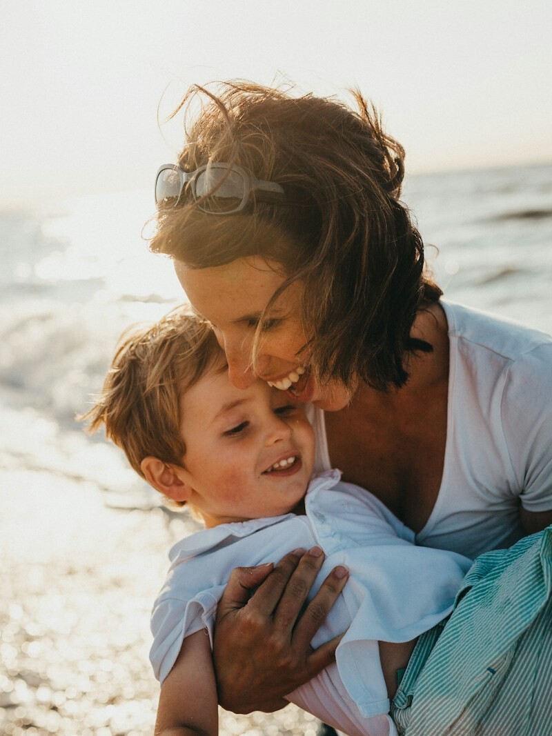 photo of mother and child beside body of water