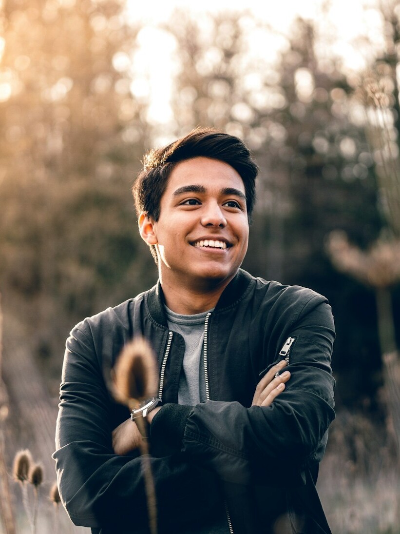 smiling man standing near green trees