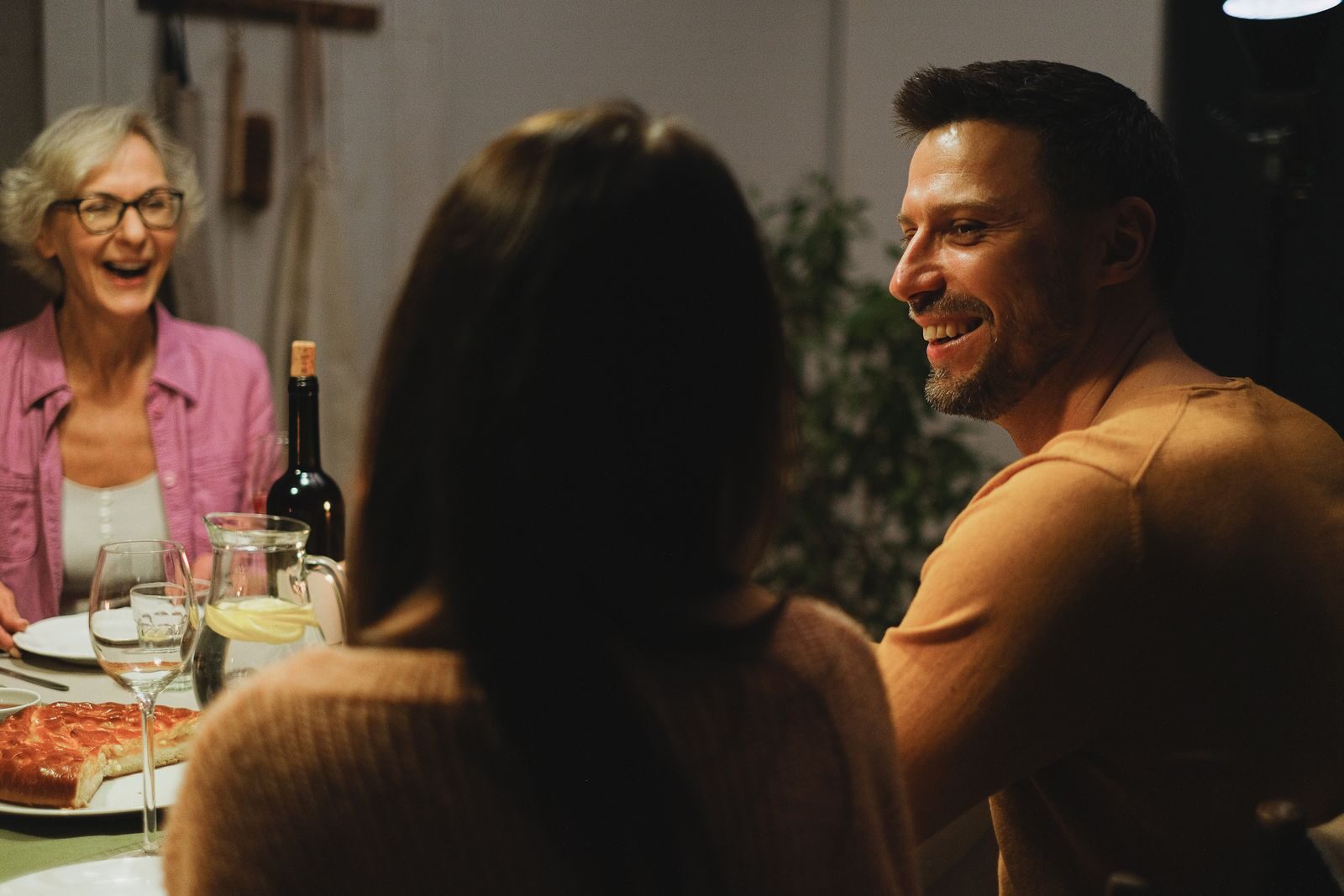 A joyful family sharing a dinner and engaging in warm conversation indoors.